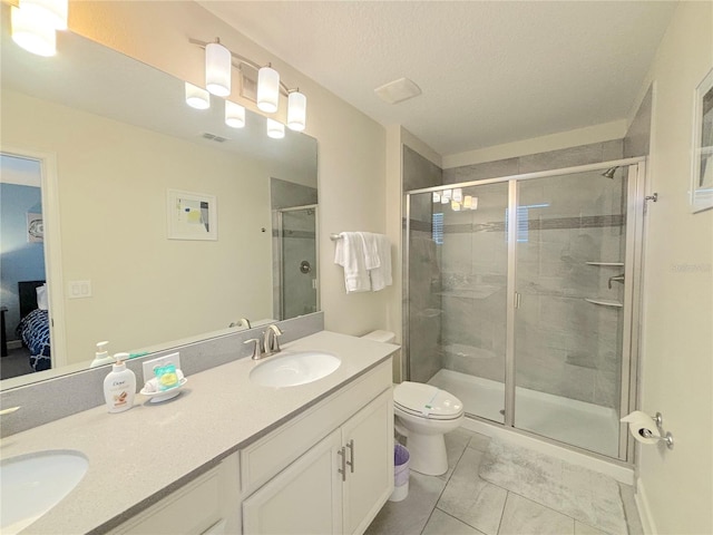 bathroom with toilet, vanity, a textured ceiling, and a shower with door