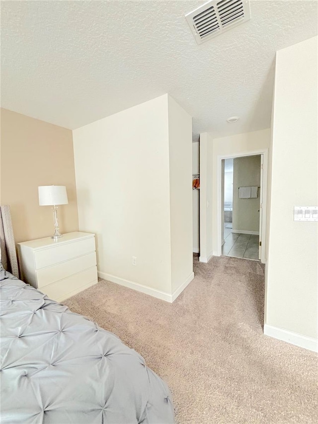 bedroom featuring a textured ceiling and light carpet