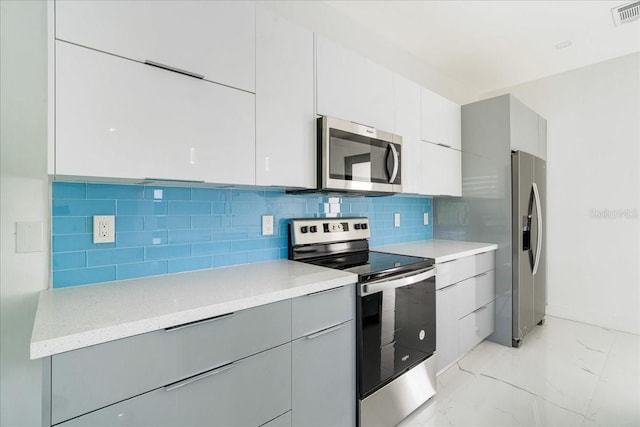 kitchen with white cabinets, gray cabinets, decorative backsplash, and appliances with stainless steel finishes