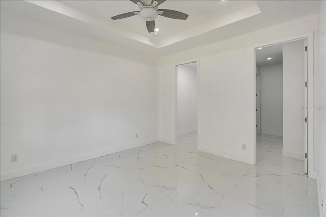 spare room featuring ceiling fan and a raised ceiling