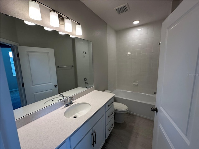 full bathroom with vanity, tiled shower / bath combo, and toilet