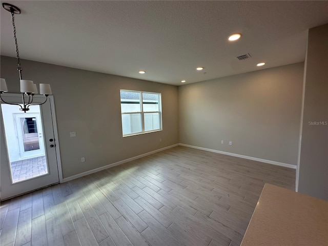 unfurnished room with light hardwood / wood-style flooring and a notable chandelier