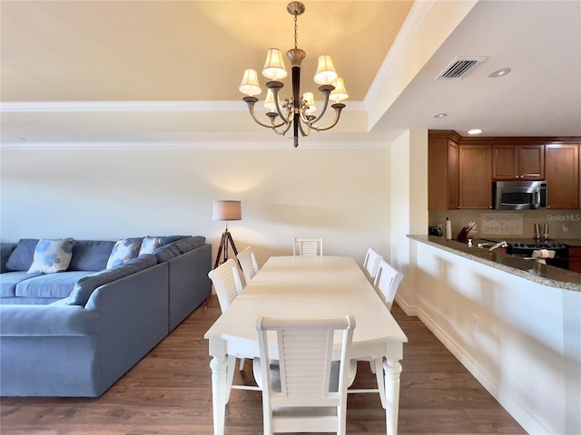 7612 Cabana Ct Unit 303, Reunion, FL 34747 - dining space featuring crown molding, a chandelier, a raised ceiling, dark wood-style floors, and recessed lighting