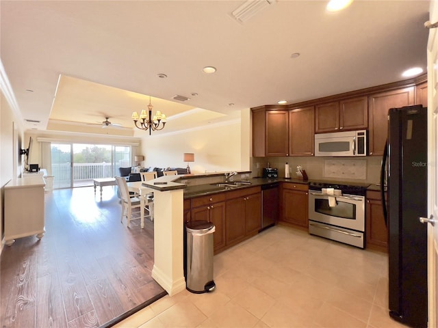 7612 Cabana Ct Unit 303, Reunion, FL 34747 - kitchen with stainless steel appliances, open floor plan, a raised ceiling, dark countertops, and ornamental molding