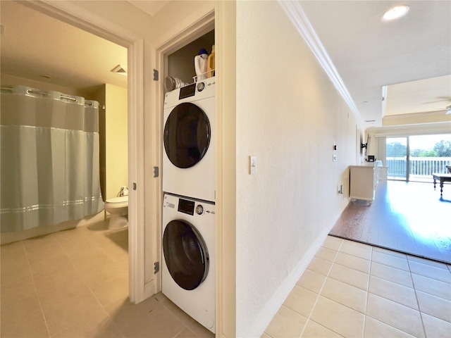 7612 Cabana Ct Unit 303, Reunion, FL 34747 - laundry room with stacked washing machine and dryer, light tile patterned floors, ceiling fan, and crown molding