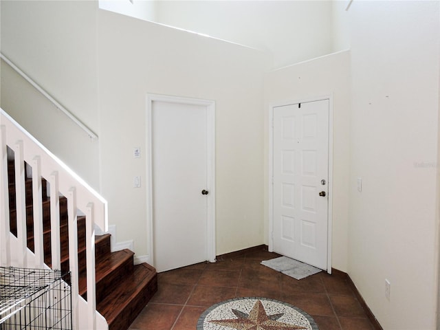 foyer featuring dark tile patterned floors and a towering ceiling