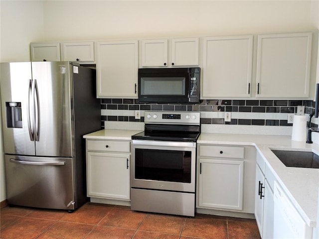 kitchen featuring appliances with stainless steel finishes, sink, white cabinets, decorative backsplash, and dark tile patterned floors