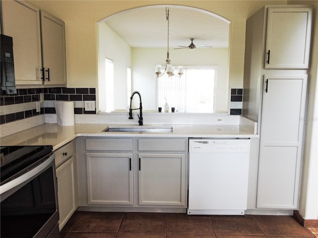 kitchen with sink, tasteful backsplash, hanging light fixtures, dishwasher, and dark tile patterned floors