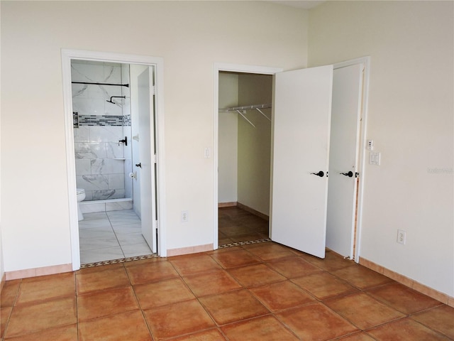 unfurnished bedroom featuring a walk in closet, tile patterned floors, and a closet