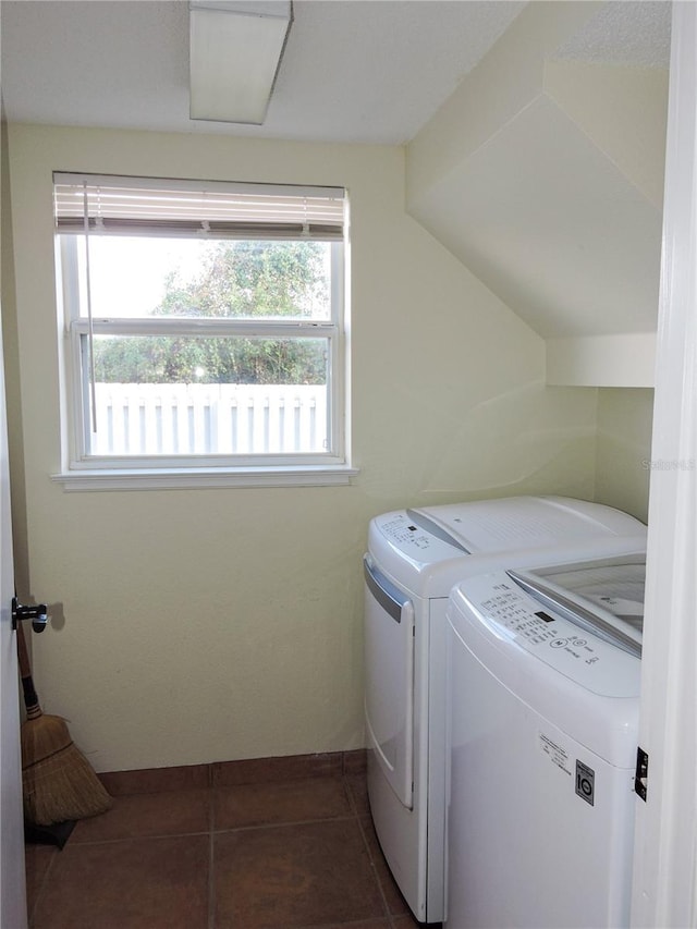 clothes washing area with a wealth of natural light, independent washer and dryer, and dark tile patterned floors