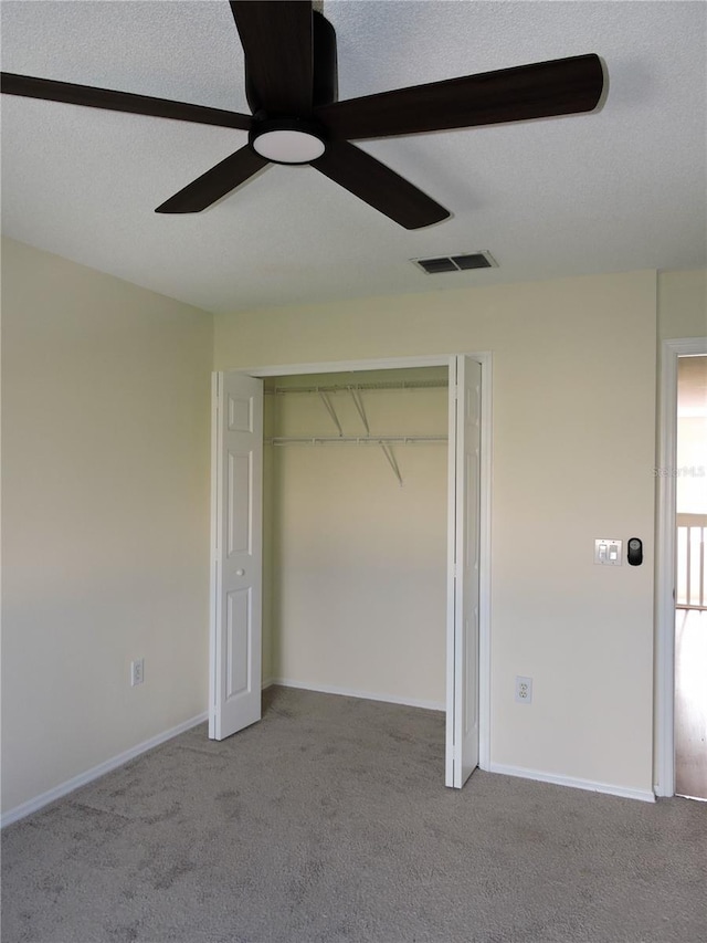 unfurnished bedroom with ceiling fan, a closet, light carpet, and a textured ceiling