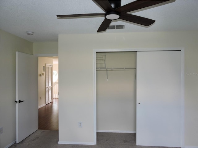 unfurnished bedroom with a textured ceiling, a closet, ceiling fan, and carpet