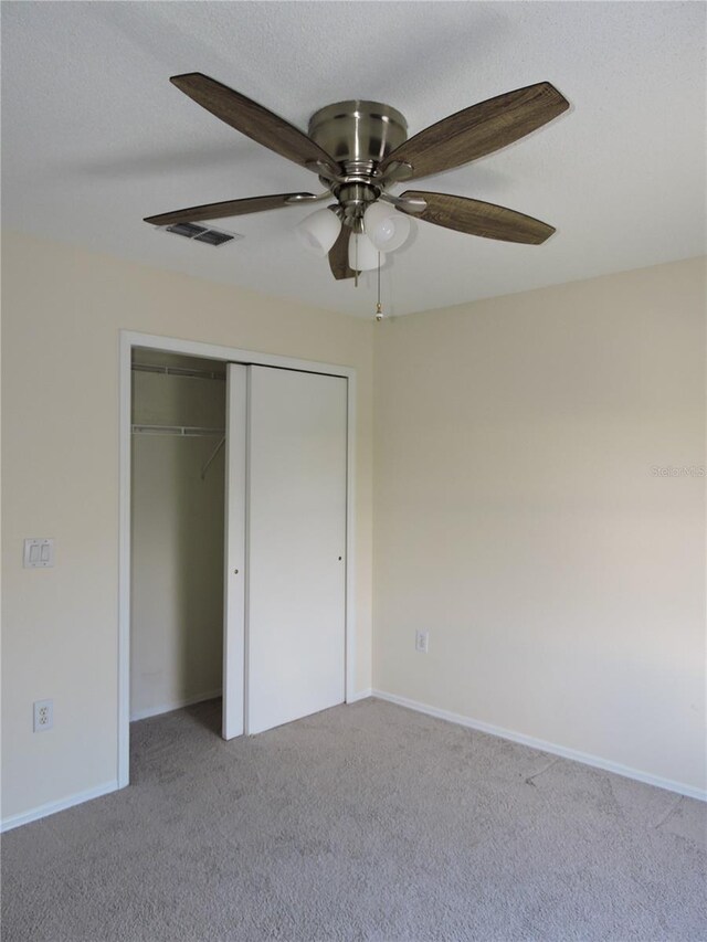 unfurnished bedroom with ceiling fan, a closet, carpet, and a textured ceiling