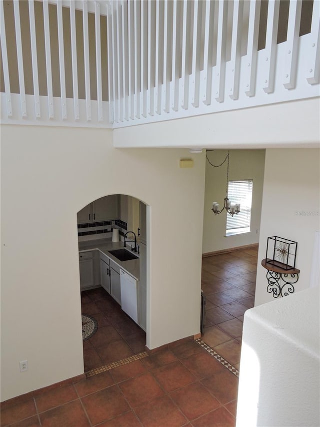 interior space featuring sink, dark tile patterned floors, white cabinetry, a high ceiling, and a chandelier