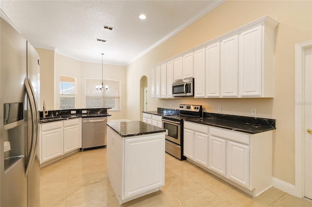 kitchen with stainless steel appliances, white cabinetry, a kitchen island, and ornamental molding