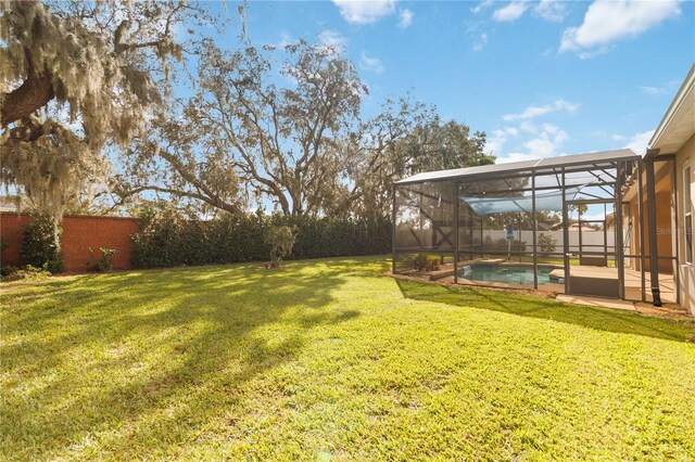 view of yard with a fenced in pool and glass enclosure