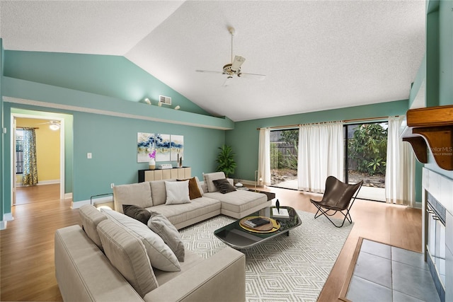 living room featuring ceiling fan, light hardwood / wood-style floors, a fireplace, and high vaulted ceiling