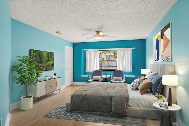 bedroom with a textured ceiling, light wood-type flooring, and ceiling fan