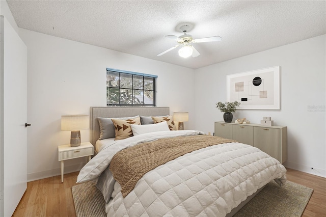 bedroom with ceiling fan, a textured ceiling, and light hardwood / wood-style flooring