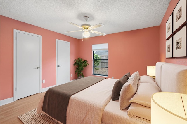 bedroom featuring ceiling fan, light hardwood / wood-style flooring, and a textured ceiling