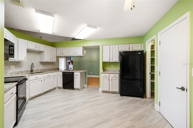 kitchen with black appliances, white cabinetry, sink, and a textured ceiling