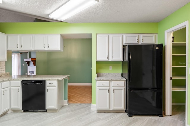 kitchen with a textured ceiling, light hardwood / wood-style flooring, white cabinetry, and black appliances