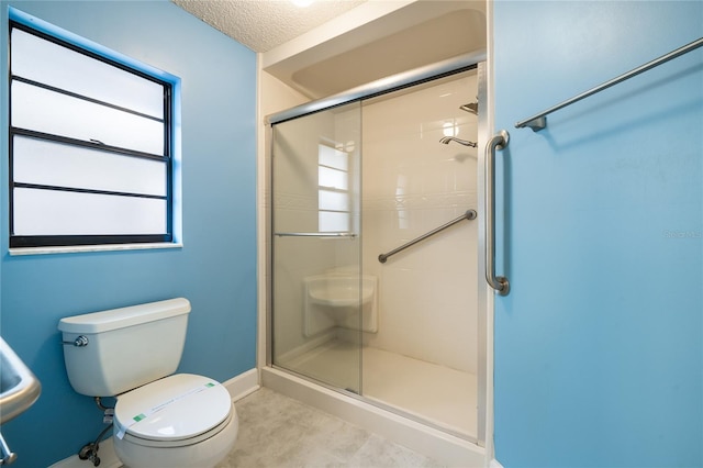 bathroom featuring a shower with door, a textured ceiling, and toilet