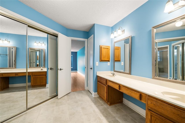 bathroom with vanity, a textured ceiling, and a shower with shower door