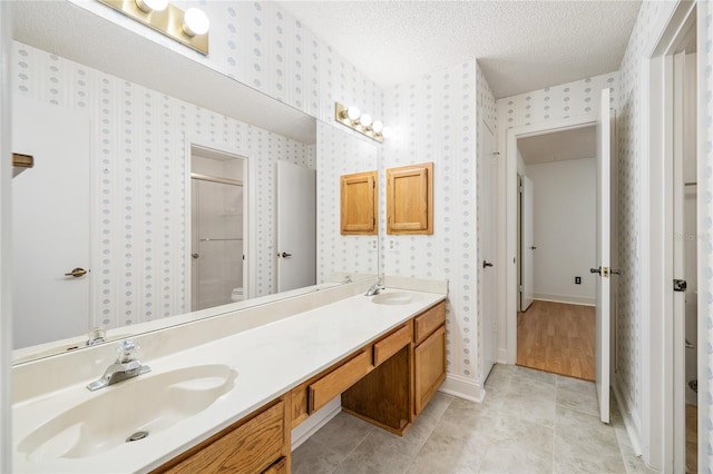 bathroom with tile patterned flooring, vanity, a textured ceiling, and toilet