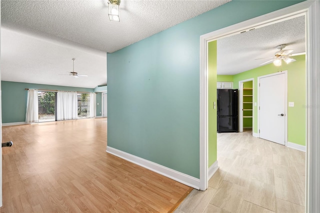 hallway with a textured ceiling and light wood-type flooring