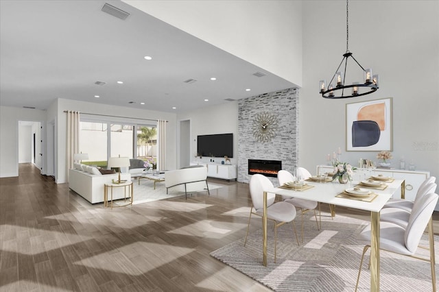 dining space featuring hardwood / wood-style floors, a stone fireplace, and a notable chandelier