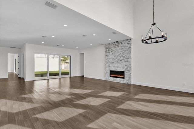 unfurnished living room featuring a fireplace, a chandelier, and hardwood / wood-style flooring