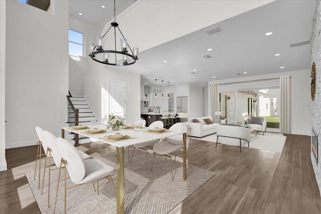 dining room featuring hardwood / wood-style floors, a towering ceiling, and an inviting chandelier