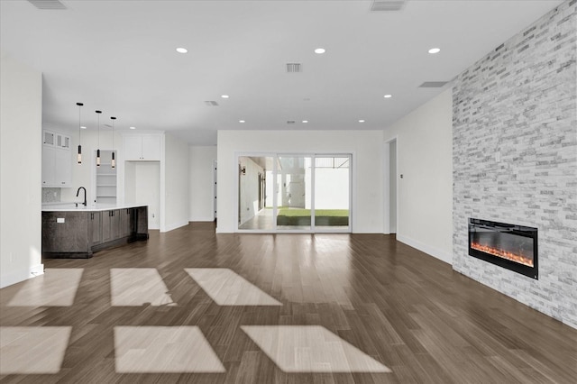 unfurnished living room with a fireplace, dark hardwood / wood-style floors, and sink