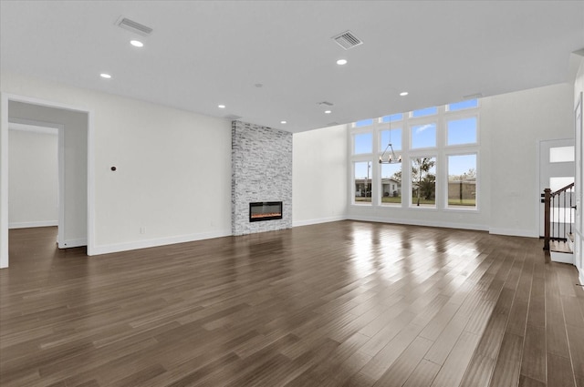 unfurnished living room with dark wood-type flooring and a stone fireplace