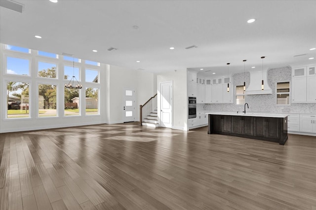 unfurnished living room featuring a chandelier, sink, and dark hardwood / wood-style flooring