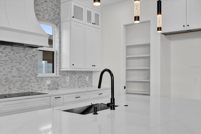 kitchen featuring white cabinetry, backsplash, decorative light fixtures, black electric cooktop, and custom exhaust hood