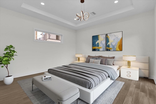 bedroom featuring hardwood / wood-style floors and a tray ceiling