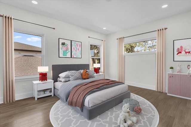 bedroom featuring hardwood / wood-style flooring, multiple windows, and radiator