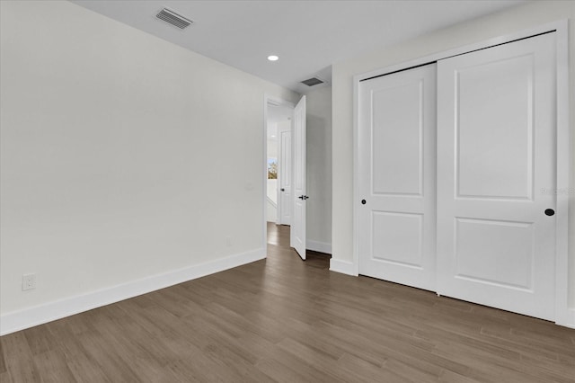 unfurnished bedroom with a closet and dark wood-type flooring