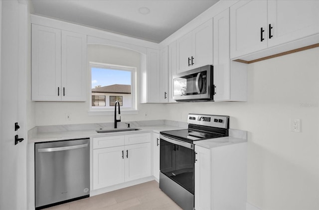 kitchen featuring light stone countertops, stainless steel appliances, white cabinetry, and sink