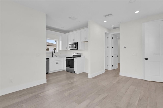 kitchen with light hardwood / wood-style flooring, white cabinets, and appliances with stainless steel finishes