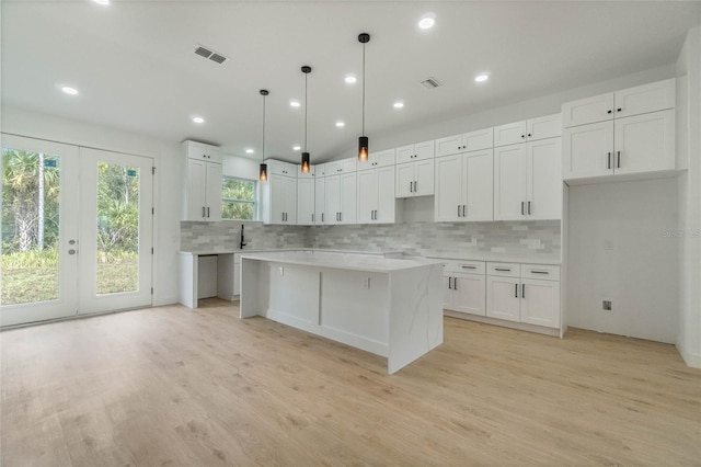 kitchen featuring white cabinetry, a center island, light hardwood / wood-style floors, and decorative light fixtures