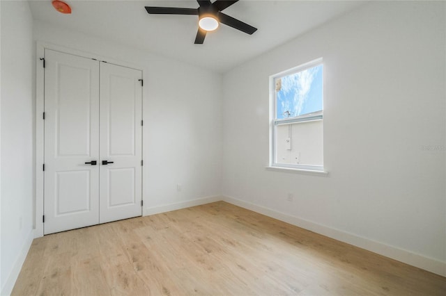 unfurnished bedroom featuring ceiling fan, a closet, and light wood-type flooring