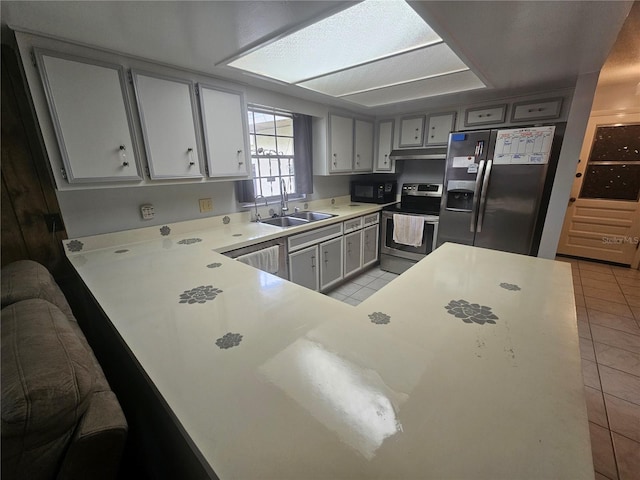 kitchen with kitchen peninsula, appliances with stainless steel finishes, sink, and light tile patterned floors