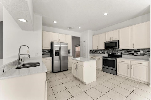 kitchen featuring a center island, sink, light tile patterned floors, appliances with stainless steel finishes, and white cabinetry