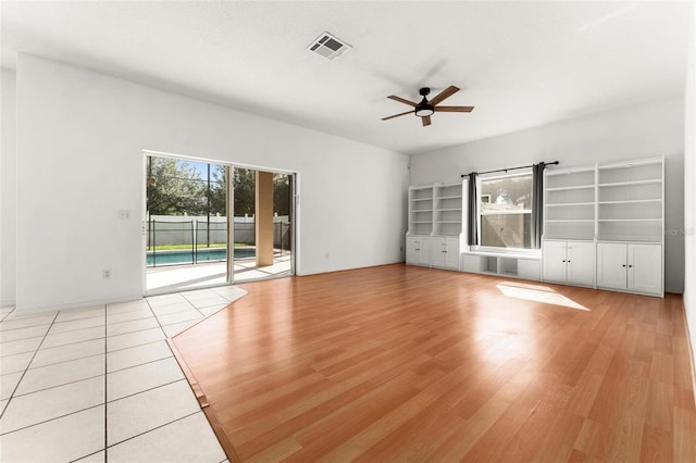 unfurnished living room featuring a wealth of natural light, ceiling fan, and light hardwood / wood-style flooring