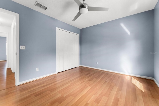 unfurnished bedroom featuring ceiling fan, a closet, and light wood-type flooring