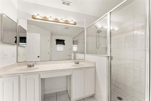 bathroom featuring tile patterned flooring, vanity, a shower with shower door, and a textured ceiling