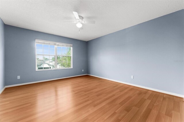 empty room with ceiling fan, light hardwood / wood-style floors, and a textured ceiling